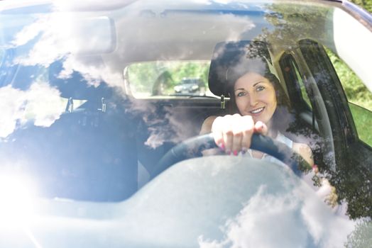 Beautiful adult happy woman driving her car in summer day