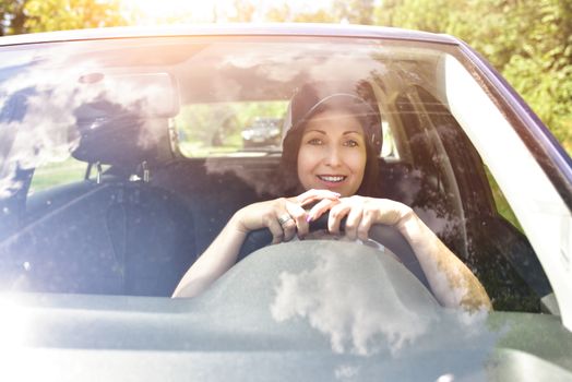 Beautiful adult happy woman driving her car in summer day