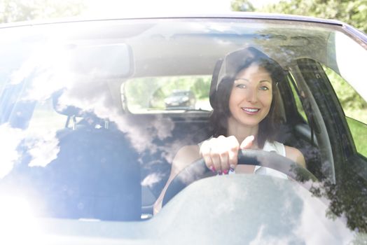 Beautiful adult happy woman driving her car in summer day