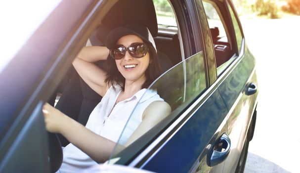 Beautiful adult happy woman driving her car in summer day
