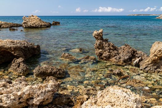 View at the rocky coastline of Plimmiri on  Rhodes island, Greece with gravel beach and rocks in the water