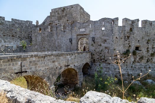 Part of the historic city wall of Rhodes town with bridge and entrance gate on Rhodes island, Greece on a sunny day