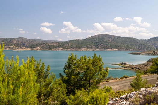 Scenic view at the Gadoura water reservoir on Rhodes island, Greece with blue and turquoise water and green landscape around the lake on a sunny day in spring