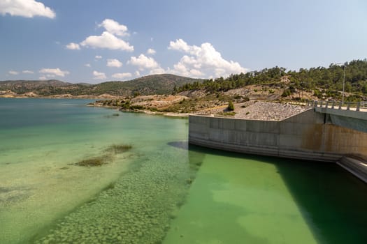 Dam of the Gadoura water reservoir on Rhodes island, Greece with  blue and turquoise water  and landscape in background