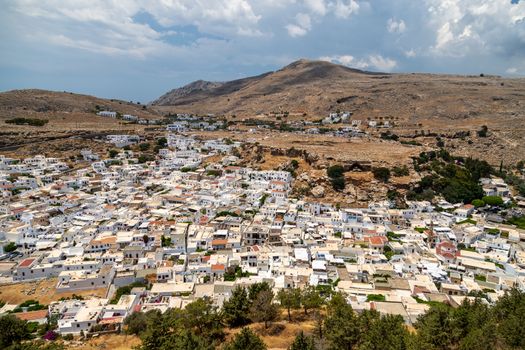 View at the city of Lindos on Greek island Rhodes with white houses and mountain in the background on a sunny day in spring