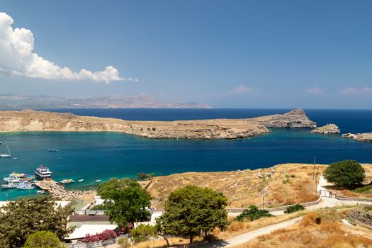 Scenic view from the acropolis on a bay and a beach with blue and turquoise water in Lindos on Rhodes island, Greece on a sunny day in spring