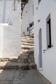 Narrow street with stairs and white houses in Lindos on Greek island Rhodes