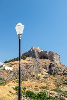 View at the acropolis of Lindos on Greek island Rhodes with street lamp in the foreground on a sunny day in spring