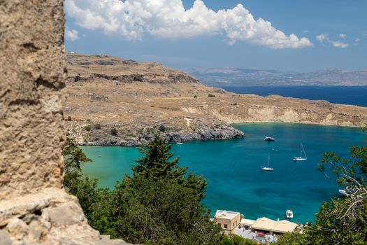 Scenic view from the acropolis on a bay and a beach with blue and turquoise water in Lindos on Rhodes island, Greece on a sunny day in spring