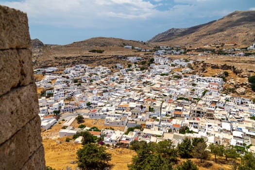 View at the city of Lindos on Greek island Rhodes with white houses and mountain in the background on a sunny day in spring