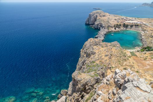 Scenic view from the acropolis of Lindos at the coastline of the mediterranean sea and St. Pauls bay with clear and turquoise water