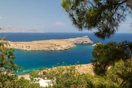 Scenic view from the acropolis on a bay and a beach with blue and turquoise water in Lindos on Rhodes island, Greece on a sunny day in spring