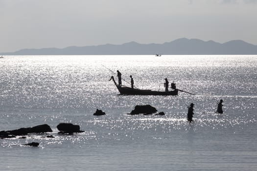 Krabi Thailand 12.16.2015 looking out to sea with fishermen silhouetted by silver sea. High quality photo