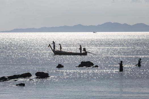 Krabi Thailand 12.16.2015 looking out to sea with fishermen silhouetted by silver sea. High quality photo