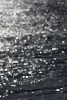 5 - Defocused vertical image of sunny water ripples, forming an abstract textured plain background of random white bokeh circles. Water theme.