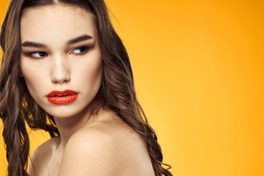 beautiful brunette red lips bare shoulders skin care yellow background. High quality photo