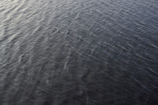 2 - Full frame gently rippled lake water. smooth sunlight gives gradual colors across the frame. Waves not cresting, evening daytime sunlight.