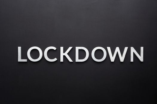 the word lockdown laid with silver metal letters on flat black background in directly above perspective.