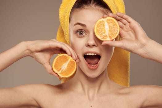 woman in a yellow towel on her head oranges close-up beige background. High quality photo