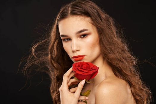 woman with a red rose on a dark background long hair makeup red lips. High quality photo