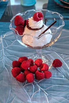 Dessert dish of cheesecake, shaved chocolate and raspberries on a glass plate.