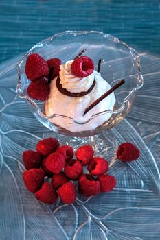 Dessert dish of cheesecake, shaved chocolate and raspberries on a glass plate.