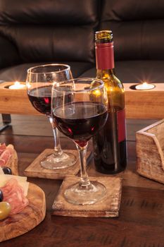 Dark red wine on a rustic wood coaster with rustic candles behind.