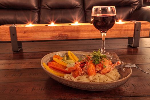 Red wine with Maine lobster over a bed of linguini with micro greens, colorful peppers and avocado sauce.