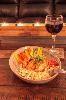 Red wine with Maine lobster over a bed of linguini with micro greens, colorful peppers and avocado sauce.