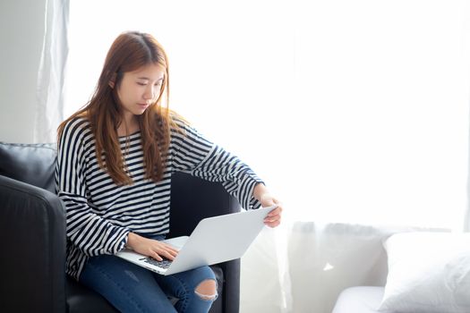 Beautiful of portrait young asian woman using laptop computer  for leisure on chair at living room, girl working online with notebook freelance, communication business concept.