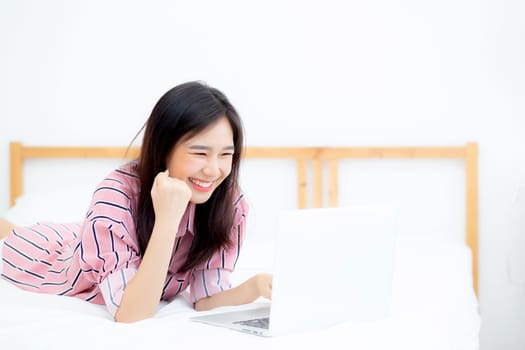 Beautiful of portrait asian young woman lying relax and leisure with laptop internet online on vacation in bedroom, cheerful of asia girl with gesture glad and success, lifestyle concept.