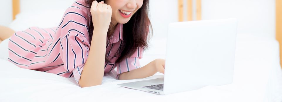 Banner website asian young woman lying relax and leisure with laptop internet online on vacation in bedroom, cheerful of asia girl with gesture glad and success, lifestyle concept.