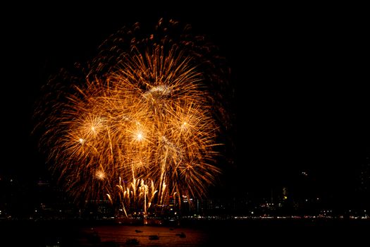 Many flashing fireworks with night cityscape background celebrate New Year.