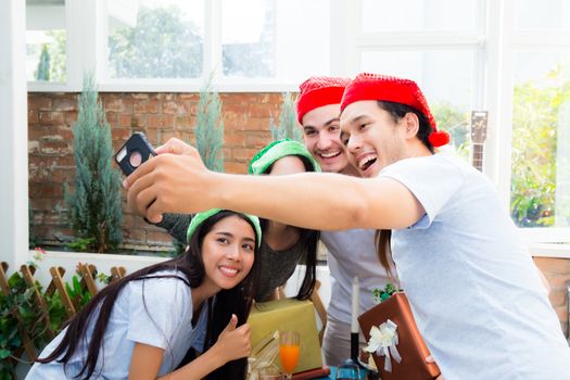 Taking a selfie portrait family or friends with smart phone on Merry Christmas and Happy New Year holiday, smile man and woman on xmas celebrating in winter happiness at home, vacation concept.