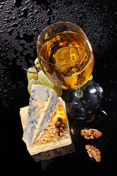 Glass of wine, piece of cheese on a glass backgound