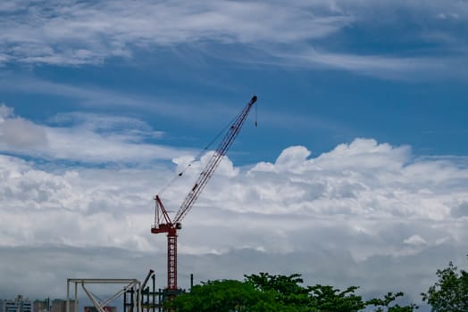 The landscape of construction tower crane with urban and sky background.