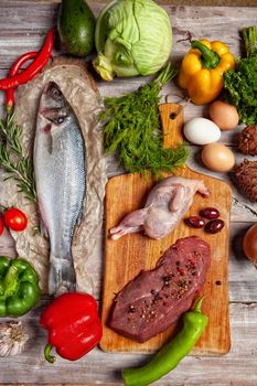 Chicken, fish and vegetables on an old wooden desk