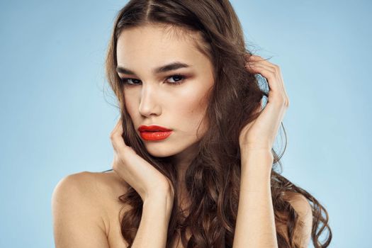Elegant brunette fashionable hairstyle bright makeup naked shoulders close-up blue background. High quality photo