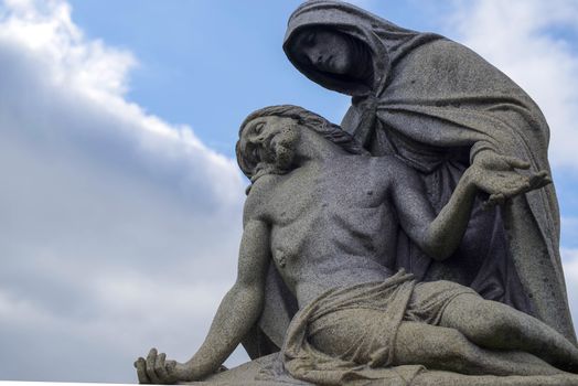 Beautiful antique statue in old cemetery, blue sky with copy space.