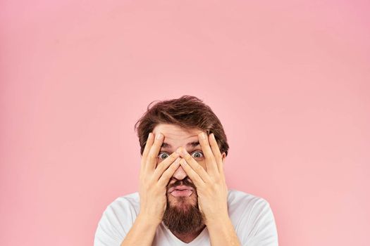 Bearded man in white t-shirt gesturing with hands facial expression close up pink background. High quality photo