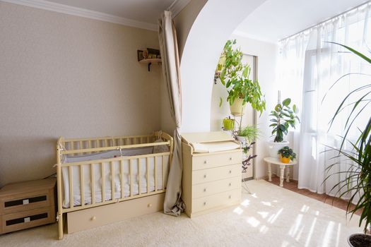 A newborn baby's crib and a changing table stand at the entrance to the glazed balcony