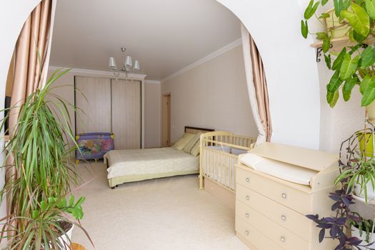 View from the glazed loggia to the interior of a spacious bedroom with furniture for a newborn baby