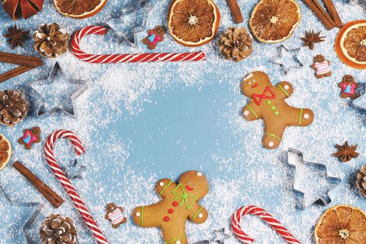 Christmas food frame. Gingerbread cookies, spices and decorations on blue background with copy space for text