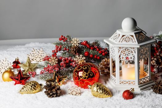 Christmas holidays card with gifts , balls and glowing lantern with candle in snow