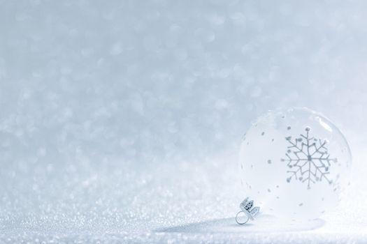 Christmas ornament transparent ball with snowflake design on silver glitter background