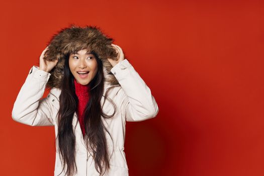 Woman in hooded jacket Asian appearance red background Copy Space