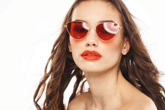 Portrait of brunette woman in sunglasses naked shoulders light background. High quality photo