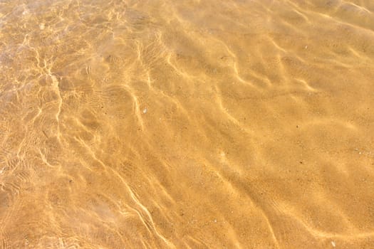 Ripples of water waves reflecting texture on a sandy beach bottom