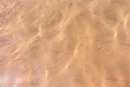 Ripples of water waves reflecting texture on a sandy beach bottom