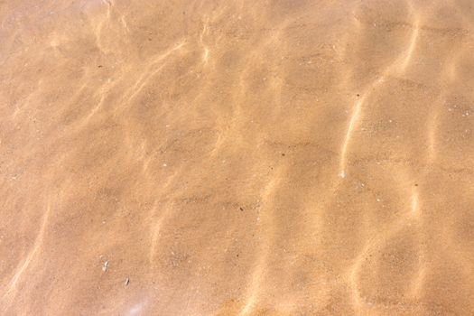 Ripples of water waves reflecting texture on a sandy beach bottom